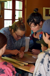 Une famille avec la mère et les enfants sont autours de differents éléments en bambou et une spécialiste du bambou leur montre des spécificités du bambou